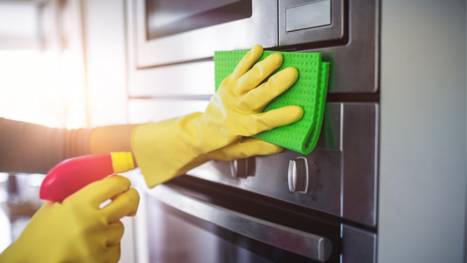 Hands cleaning stainless steel kitchen appliances